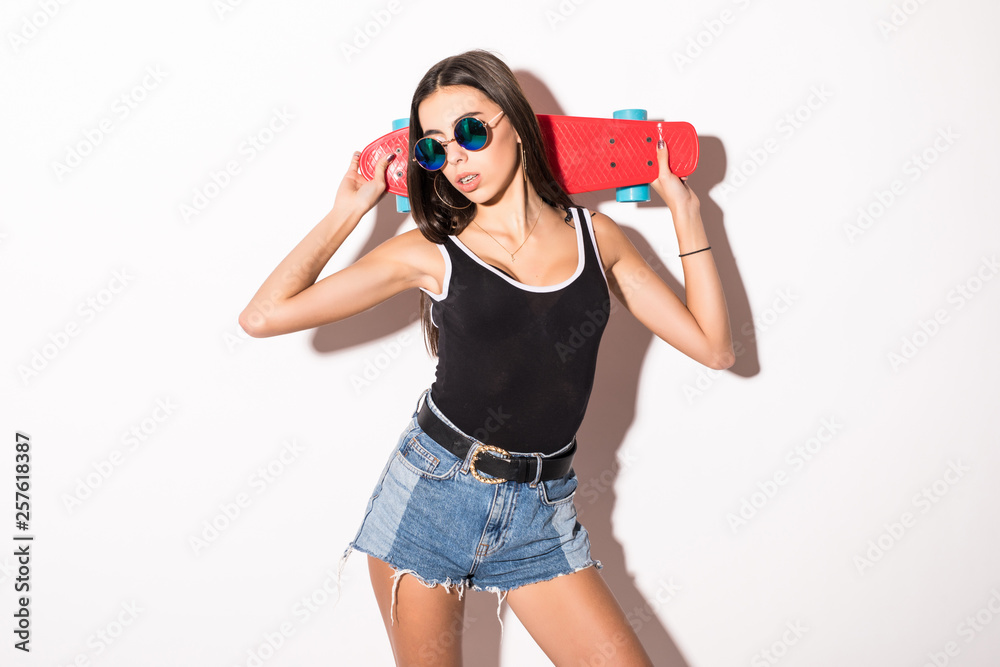 Portrait of a smiling excited brunette woman holing skateboard isolated on the white background Portrait of a smiling excited brunette woman holing skateboard isolated on the white background