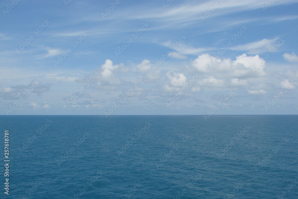 The panorama of the sea horizon, which connects the blue sky decorated with small white clouds, and the sea blue is decorated with a small ripple.