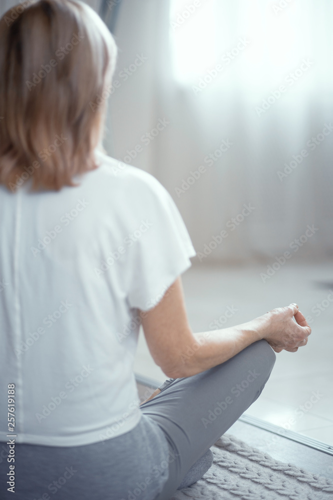 Mature woman sitting on the floor in lotus position Mature woman sitting on the floor in lotus position