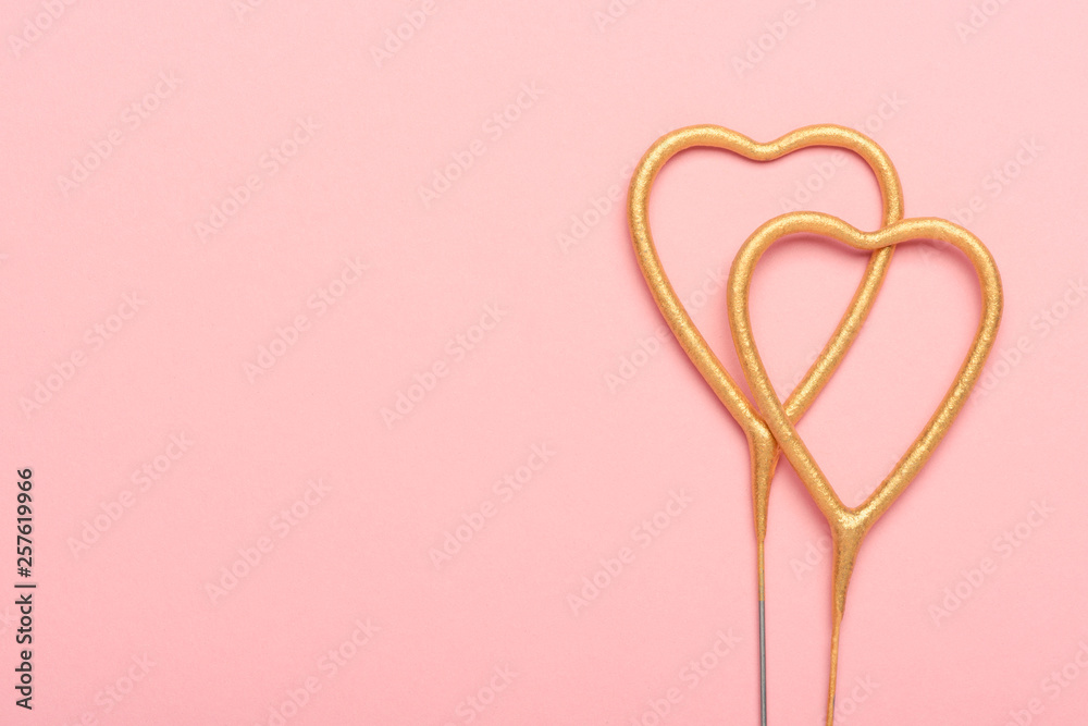Two heart shaped sparklers on pink background