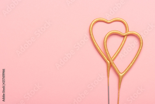Two heart shaped sparklers on pink background