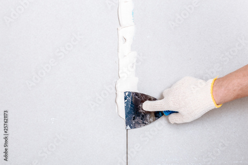 Принти на полотні Man with putty knife shows how to hide the connection place between two pieces o