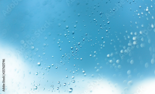 Water drops on the window  blue sky and clouds in the blurry background.