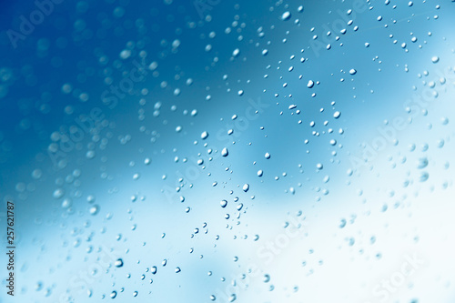 Water drops on the window, blue sky and clouds in the blurry background.