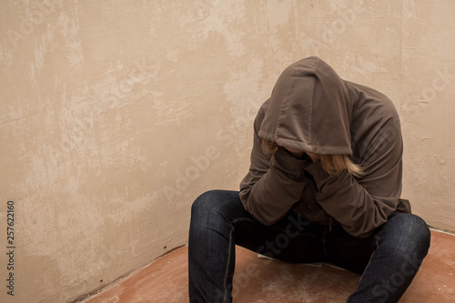 Portrait of man sad, drug addict man sitting on the floor in corner © dashtik