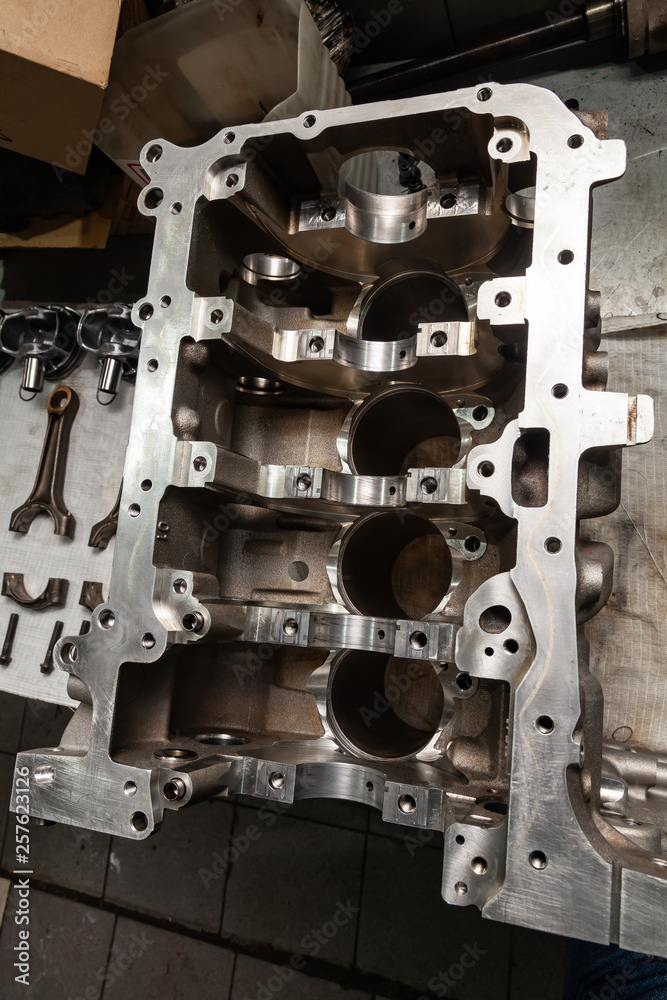 A four-cylinder engine dissembled and removed from car on a workbench in a vehicle repair workshop. Auto service industry. A four-cylinder engine dissembled and removed from car on a workbench in a vehicle repair workshop. Auto service industry.