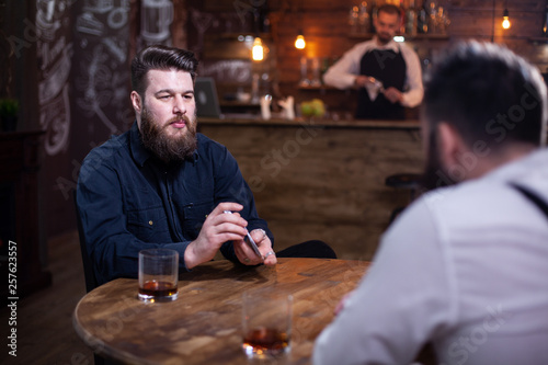 Handsome bearded men playing card in a pub and drinking whiskey