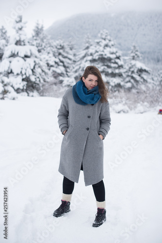 young woman on snow in greay coat 