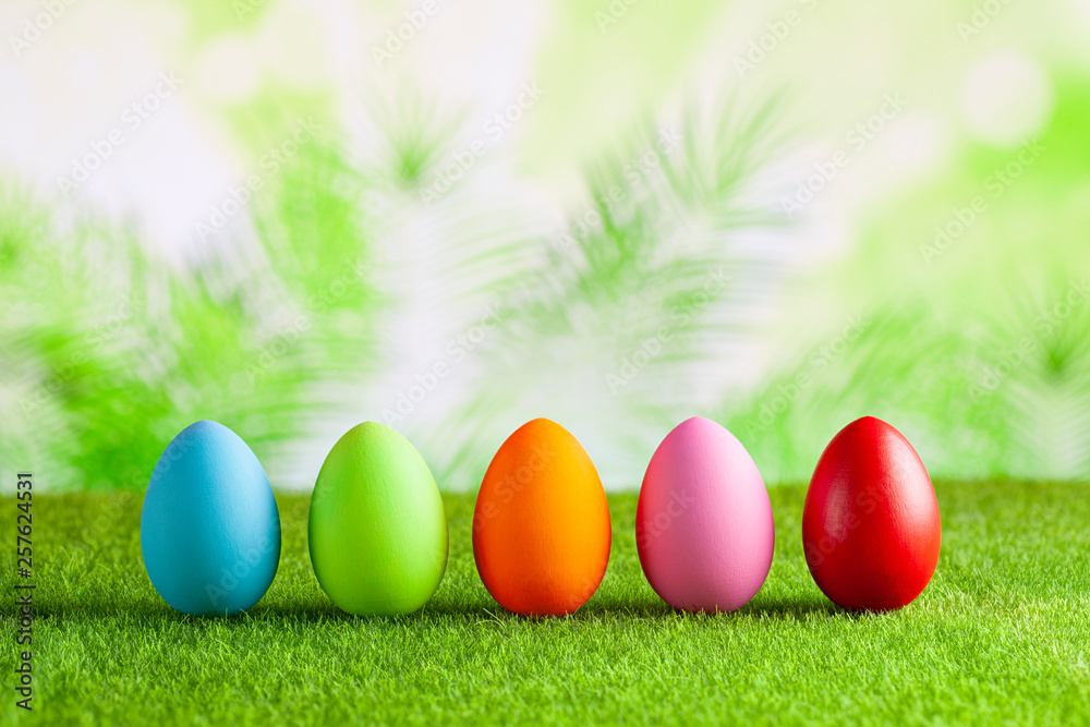 Fototapeta premium Happy Easter - Colored eggs on grass and green abstract background