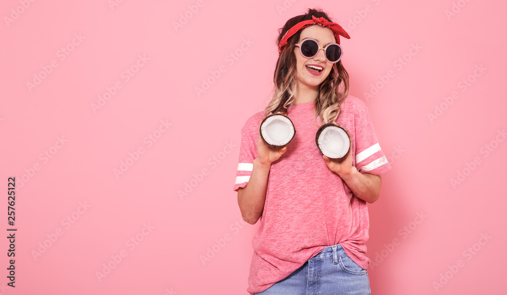 Obraz premium Portrait of a girl with coconuts, on a pink background