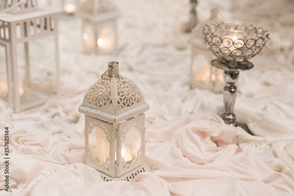 Pale toned candle holders on wrinkled cloths, wedding decorations