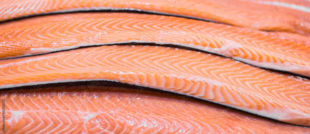 Sliced raw, not cooked salmon, red fish, lying in the ice on the counter in the supermarket