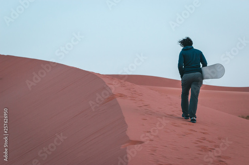 Boy makes sandboarding in the Sahara desert  Morocco. Safari desert camp in Merzouga