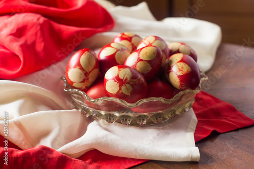 Traditional red Easter eggs with rose leaf, in basket on wood background. 