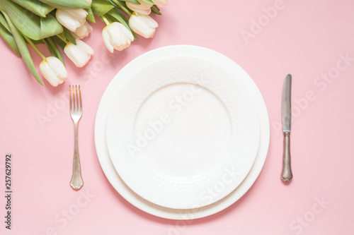 Elegant table setting with white tulip on pink table. Romantic spring dinner.