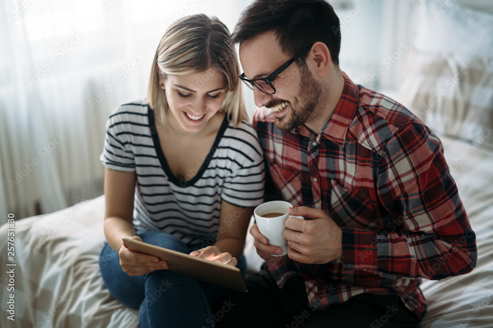 Young happy couple using tablet in bedroom Young happy couple using tablet in bedroom