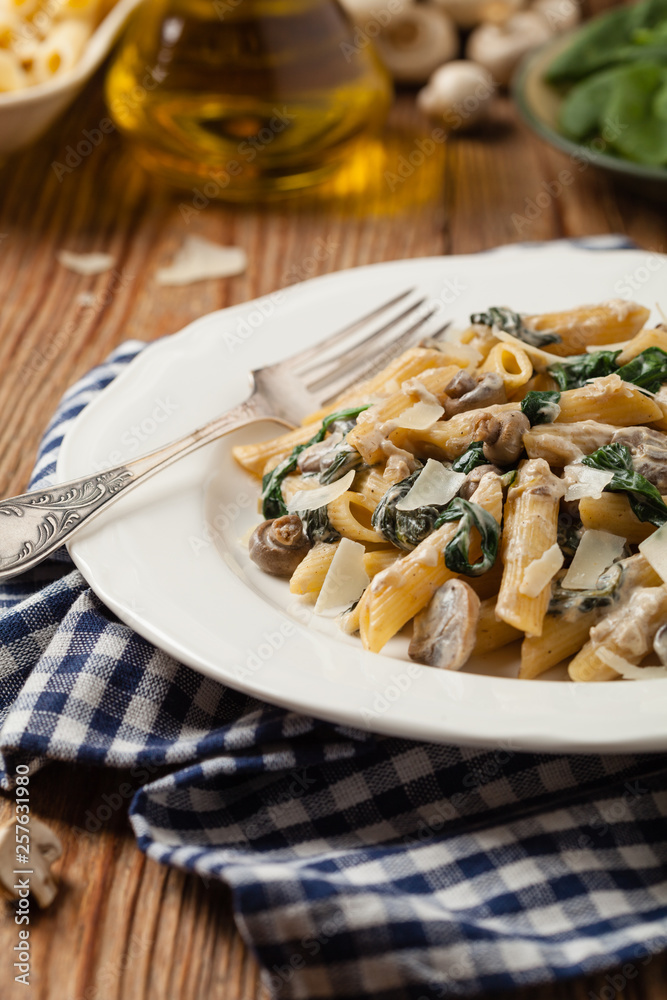Penne pasta with spinach and mushrooms. Sprinkled with cheese. Penne pasta with spinach and mushrooms. Sprinkled with cheese.