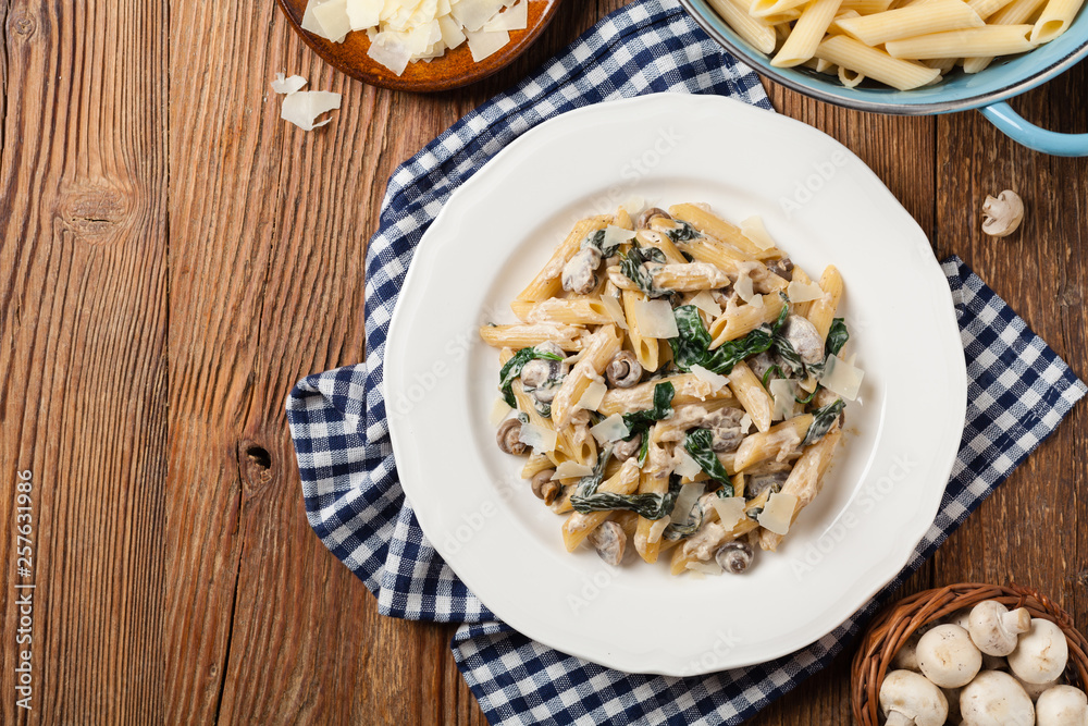 Penne pasta with spinach and mushrooms. Sprinkled with cheese.