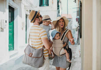 A young family with two toddler children walking in town on summer holiday.