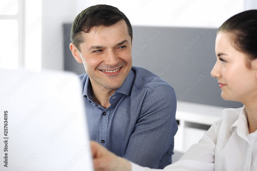 Cheerful smiling businessman and woman working with computer in modern office. Headshot at meeting or workplace. Teamwork, partnership and business concept Cheerful smiling businessman and woman working with computer in modern office. Headshot at meeting or workplace. Teamwork, partnership and business concept