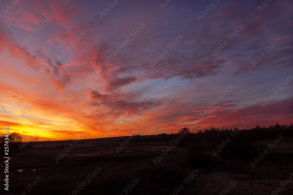 Natural Sunset of sun over field or meadow. Earth in the shadow of a colorful sky