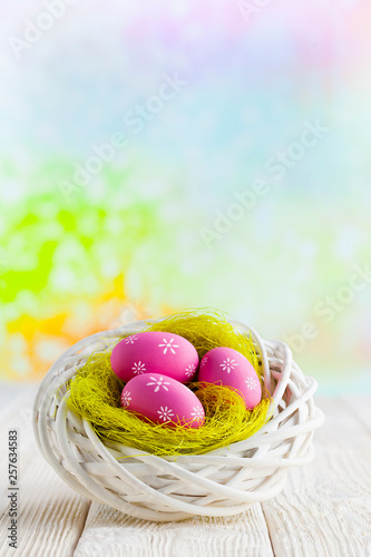 Easter eggs in the nest and wooden table on abstract background