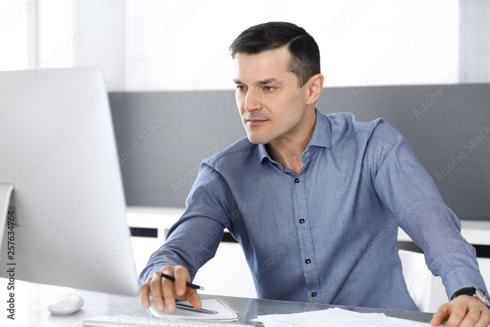 Fototapeta premium Businessman working with computer in modern office. Headshot of male entrepreneur or company director at workplace. Business concept