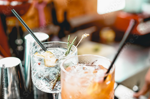 Cocktails served on bar counter prepared with gin, rosemary, paper and orange juice - Drink, nightlife, lifestyle concept - Focus on top crystal glass