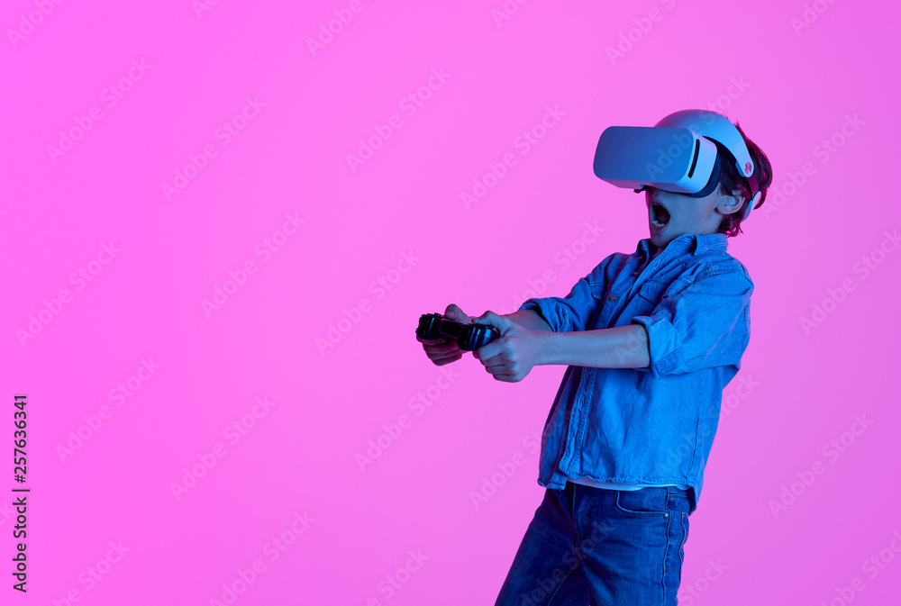 Stunned kid playing in VR goggles 
