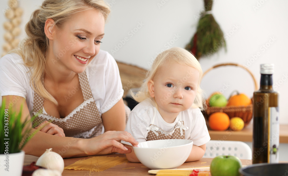Happy mother and little daughter cooking in kitchen. Spending time all together, family fun concept Happy mother and little daughter cooking in kitchen. Spending time all together, family fun concept