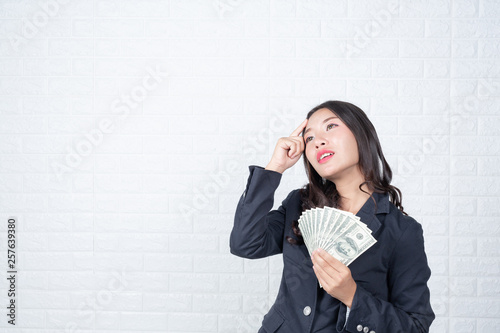 A young businesswoman holds a dollar note on a white brick wall background. photo