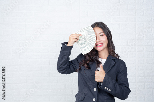 A young businesswoman holds a dollar note on a white brick wall background. photo