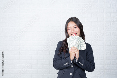 A young businesswoman holds a dollar note on a white brick wall background. photo