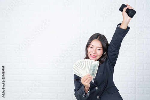A young businesswoman holds a dollar note on a white brick wall background. photo