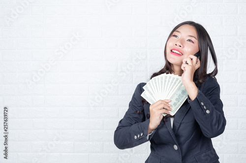 A young businesswoman holds a dollar note on a white brick wall background. photo