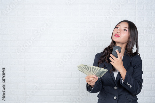 A young businesswoman holds a dollar note on a white brick wall background. photo