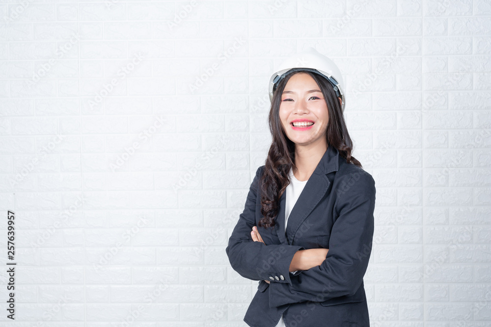 Woman of engineering holding a hat, Separate the white brick wall made gestures with sign language. Woman of engineering holding a hat, Separate the white brick wall made gestures with sign language.