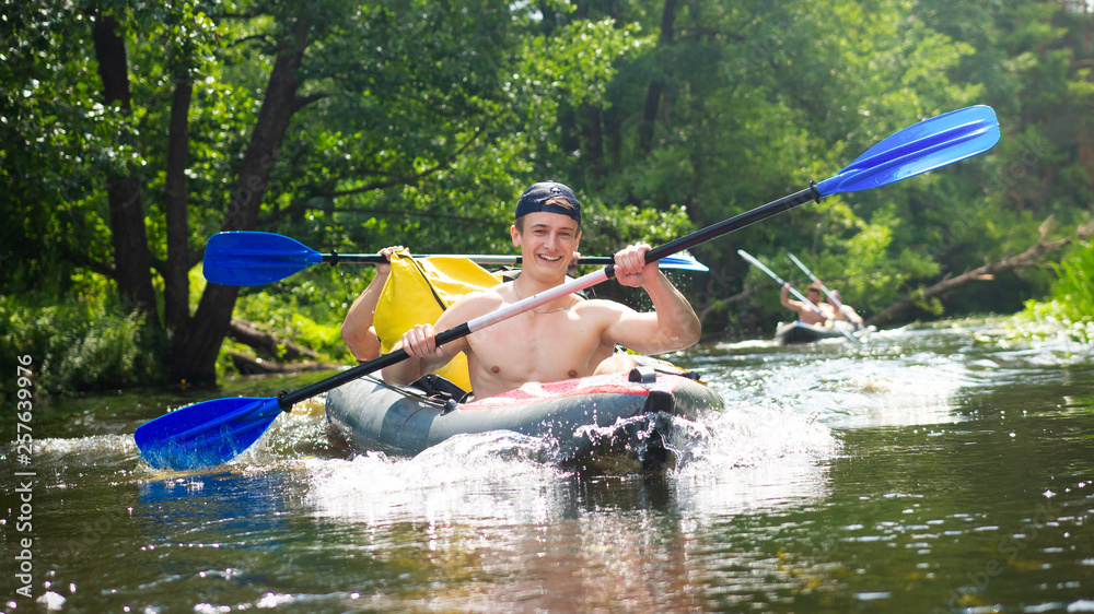 Friends having happiness during rafting on river. Guys in canoe with paddles. Rowing in boat at weekend
