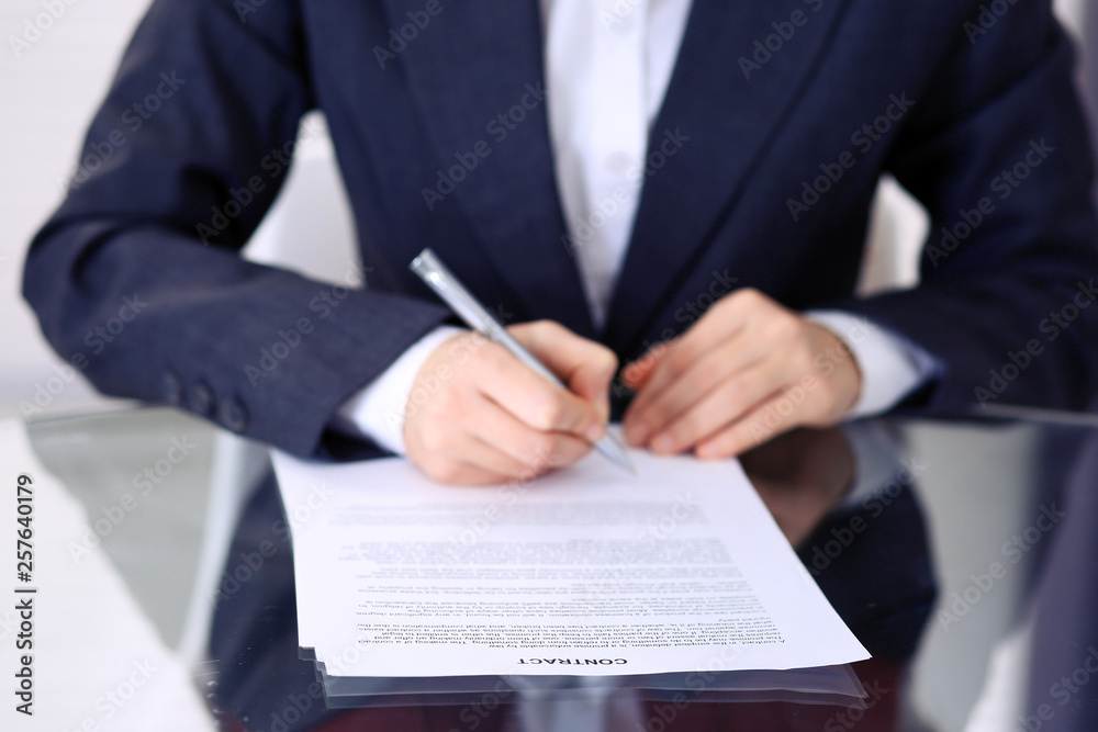 Unknown female hands with pen over document of contract. Agreement signing or business concept Unknown female hands with pen over document of contract. Agreement signing or business concept