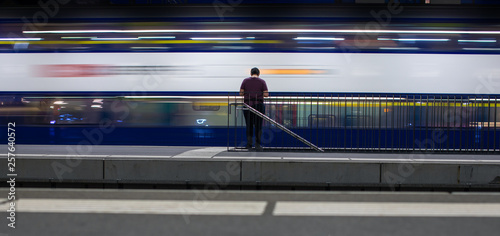 People in a trainstation with motion blurred trains moving fast (color toned image) photo