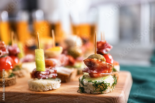 Tasty canapes on wooden board, closeup photo