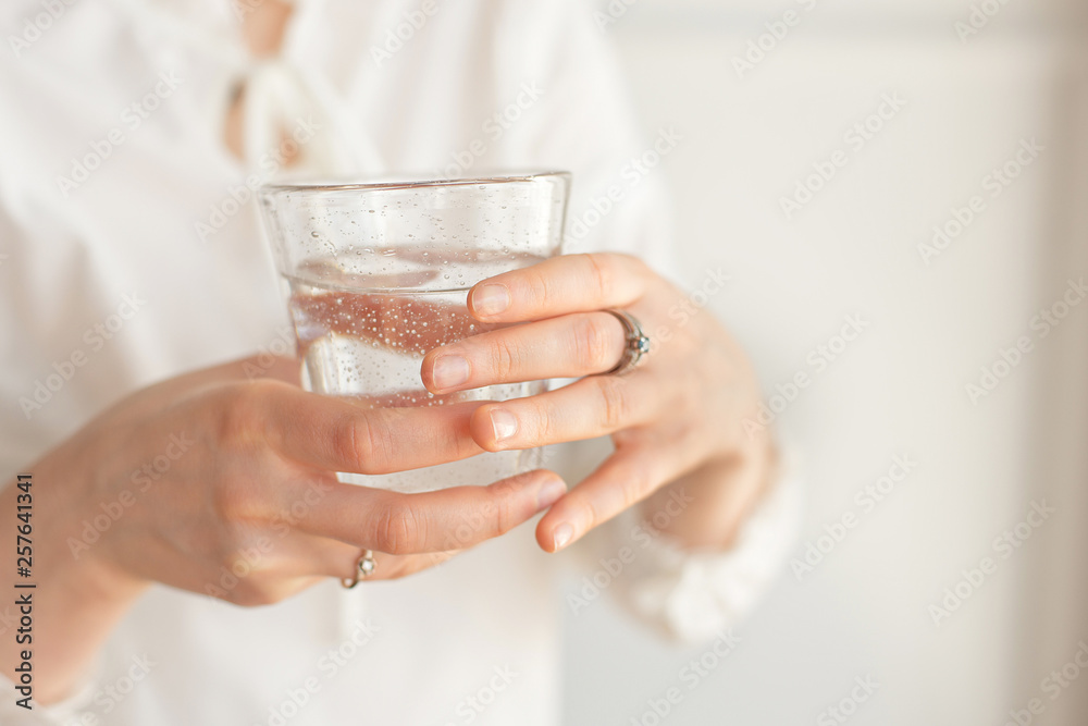Female hands holding a clear glass of water.A glass of clean mineral water in hands, healthy drink Female hands holding a clear glass of water.A glass of clean mineral water in hands, healthy drink