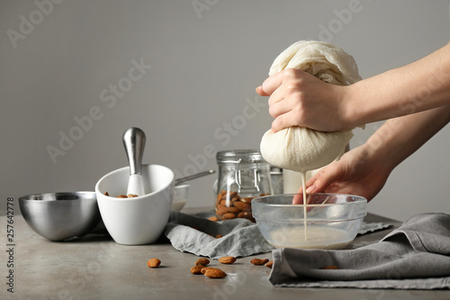 Woman making healthy almond milk in kitchen