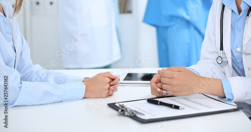 Doctor and patient discussing something, just hands at the table, white background