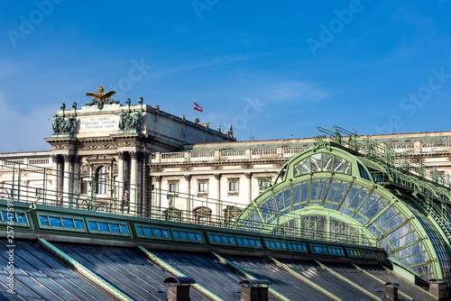 Austria, Vienna: Famous old metal roof construction of Palmenhaus (Palm Tree House) with Neue Burg and blue sky in the city center of the Austrian capital - concept architecture history travel.