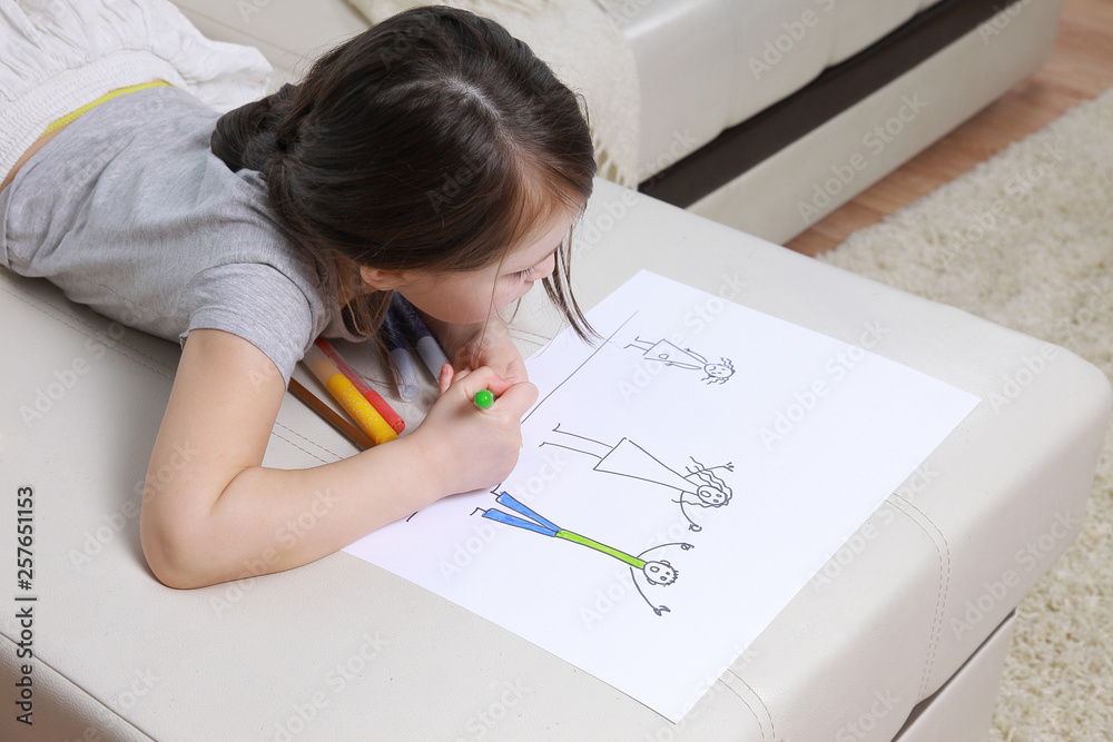 Girl in bright clothing draws a picture of the family. Light room Girl in bright clothing draws a picture of the family. Light room