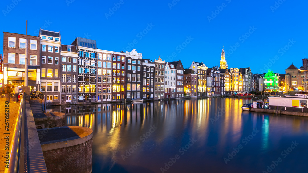 Amsterdam architecture along Damrak canal at night, Netherlands