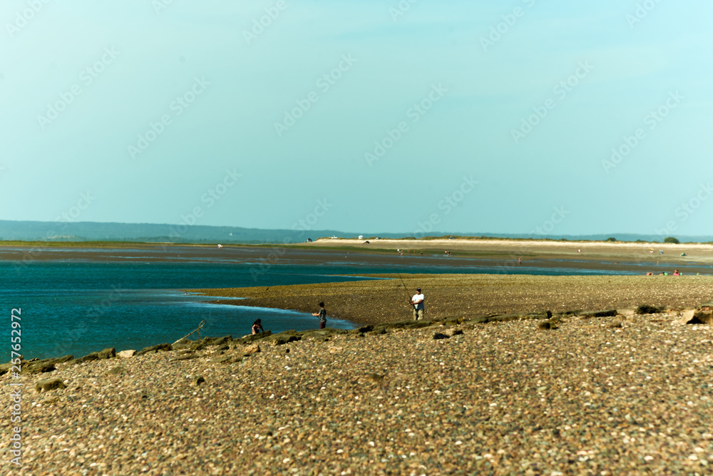Fototapeta premium Beach with blue sky and against the light, soft brown sand colors, intense blue, soft blues and white line of the horizon and saturation of colors.