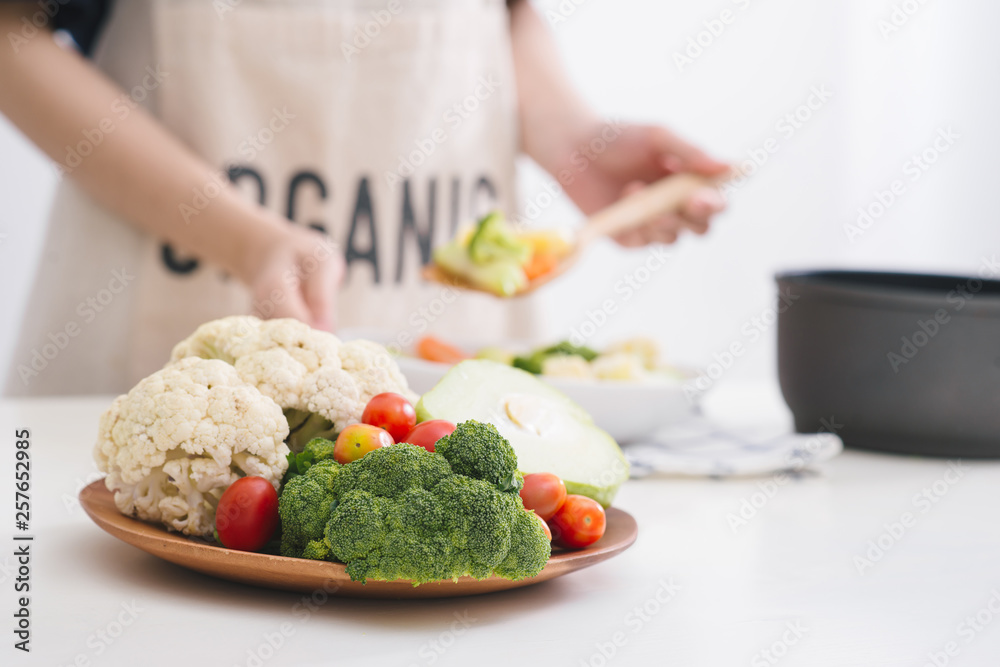 Woman in kitchen cooking stir vegetables on pan and tasting.