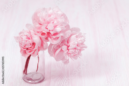 Beautiful peony flower in vase on blurred background. Pink bouquet in vase. Pastel colored flowery greeting card. Soft selective focus.